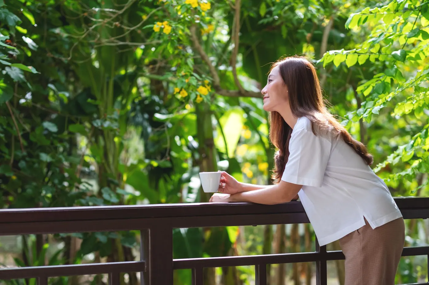 A woman enjoying clean, fresh air by a lush green garden